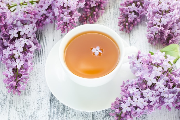 Taza de té de hierbas y lila sobre fondo de madera