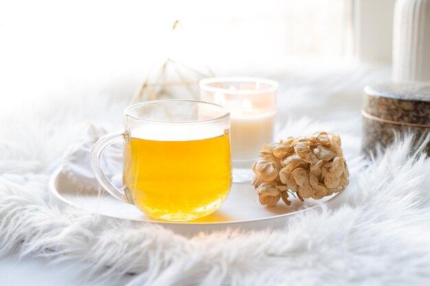 Taza de té de hierbas y velas encendidas en bandeja decorativa blanca redonda