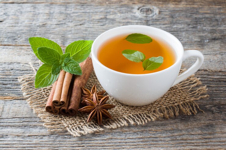 Taza de té con hojas de menta fresca y anís de canela sobre madera