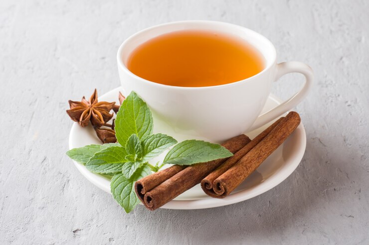 Taza de té con hojas de menta fresca y anís estrellado sobre un hormigón gris