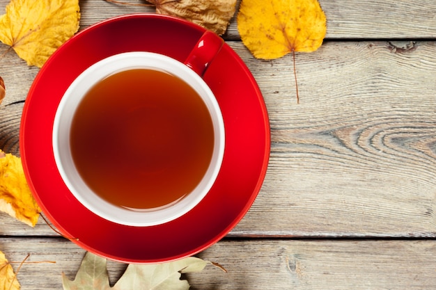 Foto taza de té y hojas de otoño en la mesa