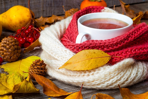 Una taza de té con hojas de otoño sobre una mesa de madera. Bueno para tu salud.