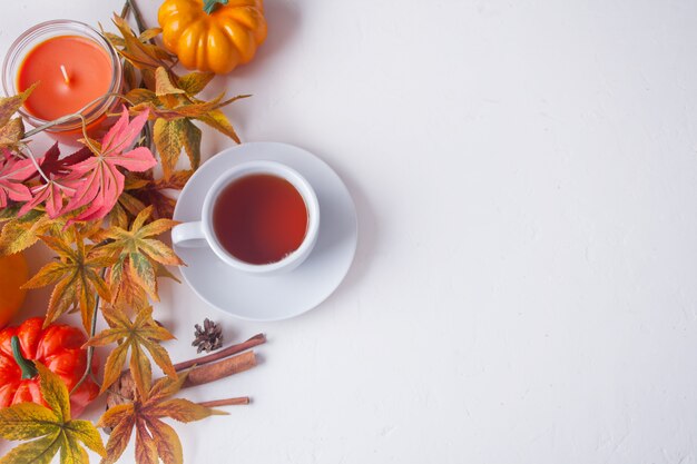 Taza de té, hojas de otoño, vela, calabaza en blanco.