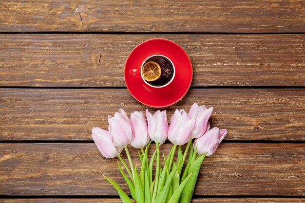 Taza de té inglés con tulipanes de primavera en madera