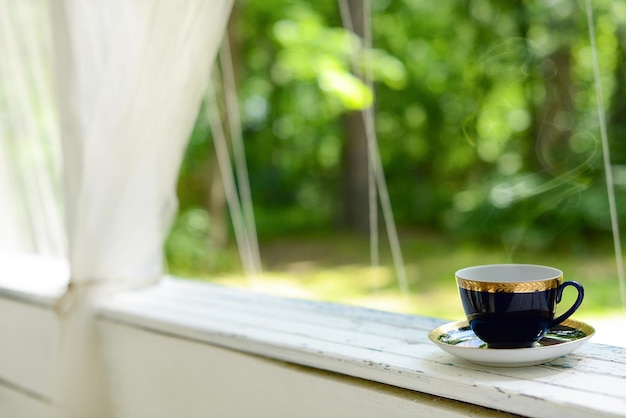 Taza de té en el jardín verde de verano Bebida caliente en taza azul en la terraza del jardín Taza con café negro caliente