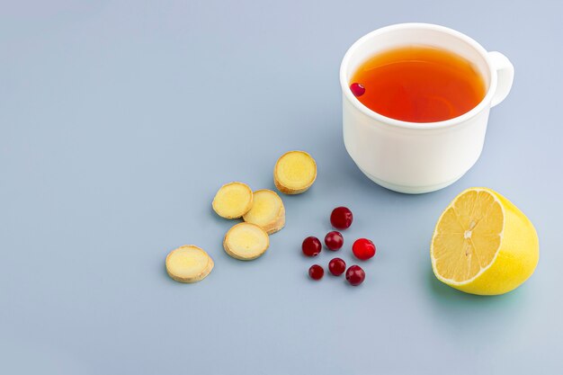 Taza de té, jengibre, limón y arándano como remedios caseros en azul