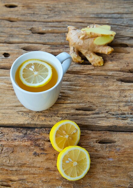 Taza de té de jengibre con limón en madera