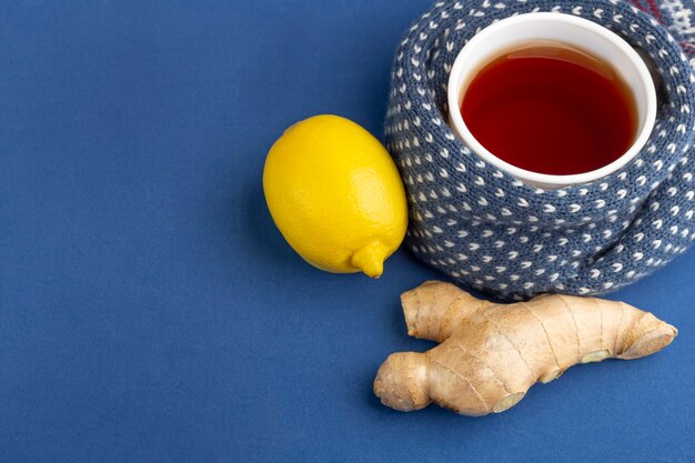 Taza de té, jengibre y limón sobre azul