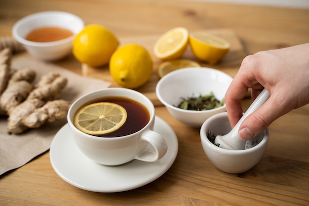 Taza de té de jengibre con limón sobre mesa de madera.