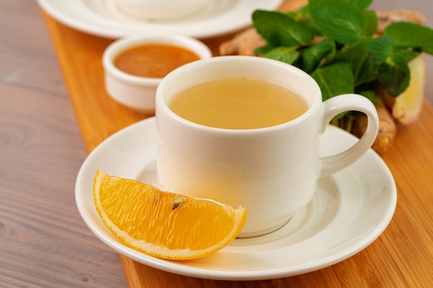 Taza de té con jengibre y menta en la mesa de madera de cerca