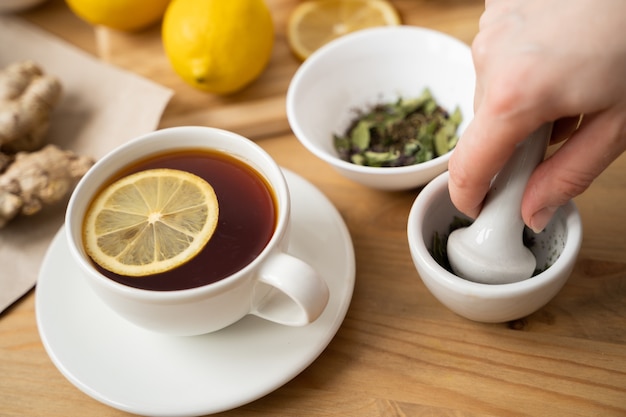 Taza de té de jengibre con miel y limón sobre mesa de madera