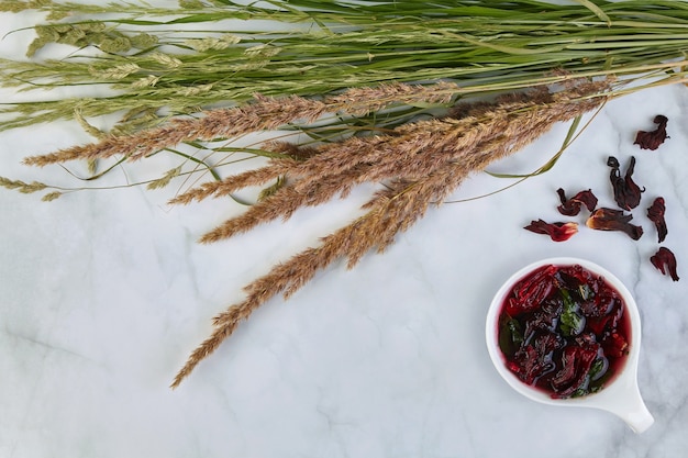 Una taza de té karkade de frutas refrescantes con menta y un ramo de hierbas silvestres sobre una mesa de luz. Una bebida refrescante en el calor del verano.