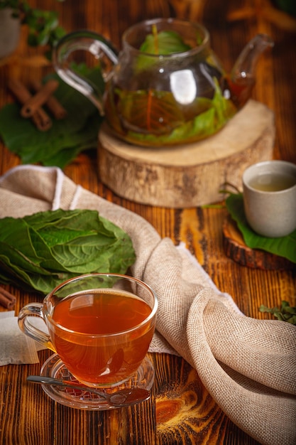 Taza de té de Kratom con hojas de kratom verdes frescas o Mitragyna speciosa sobre fondo de madera