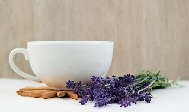 Taza de té de lavanda caliente saludable y ramo de lavanda en una mesa de madera. Concepto de estilo de vida saludable.