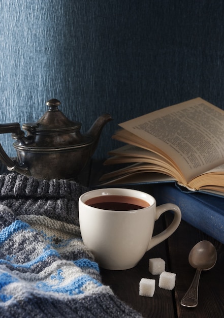 Taza de té, libro y gorro de lana sobre una mesa de madera