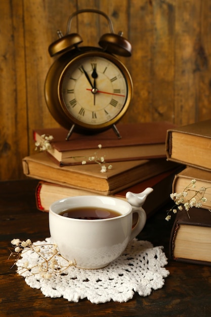 Taza de Té con libros y reloj sobre fondo de madera