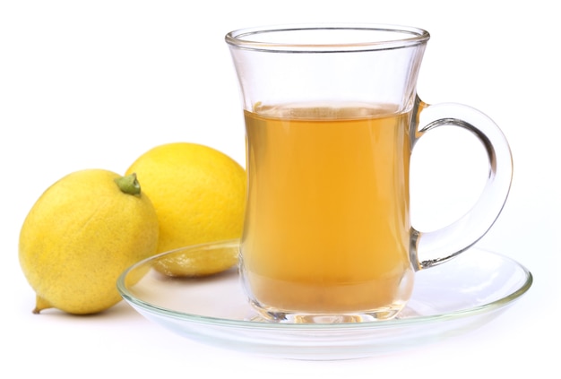 Taza de té con limón entero sobre fondo blanco.