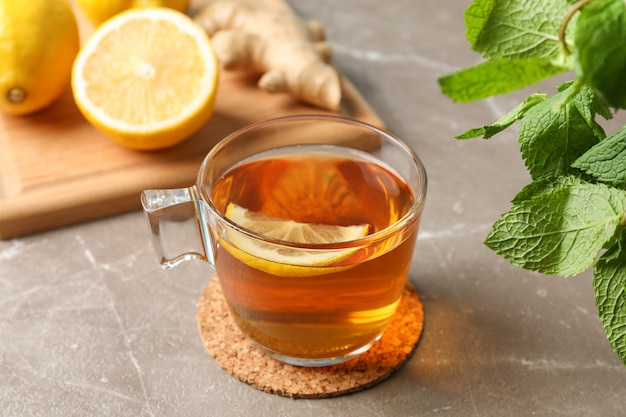 Taza de té, limón, jengibre y menta en gris, de cerca