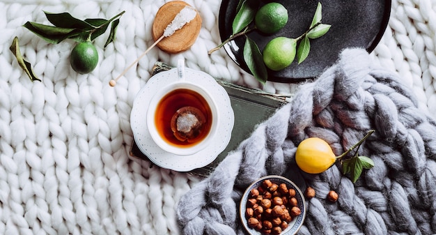 Una taza de té, limón y una manta blanca. Instagram. Vista desde arriba. Banner largo