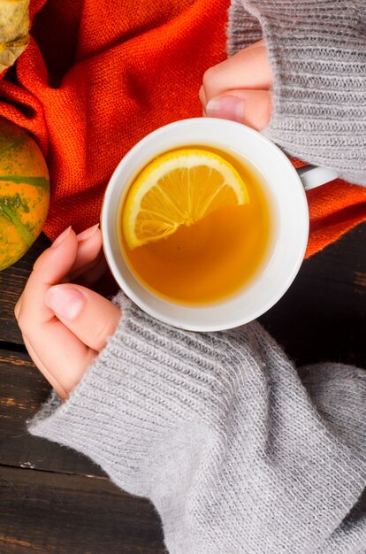 Taza de té con limón en la mesa de madera oscura con hojas de otoño