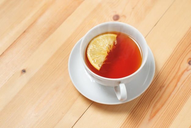 Taza de té con limón en la mesa de madera