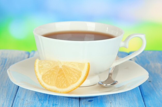 Foto taza de té con limón en la mesa sobre fondo azul.