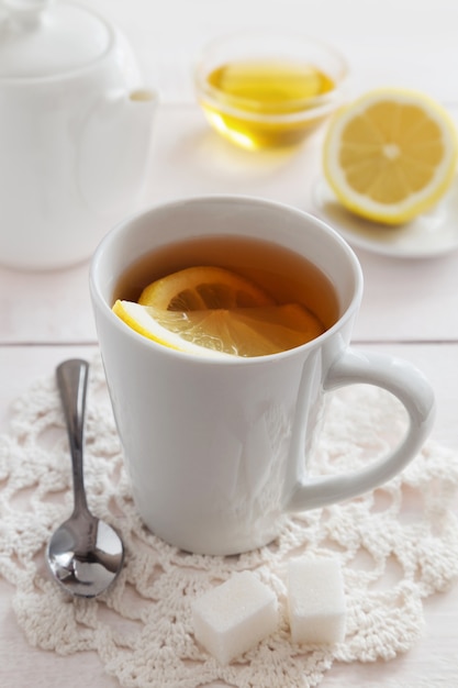 Taza de té de limón con miel y una tetera