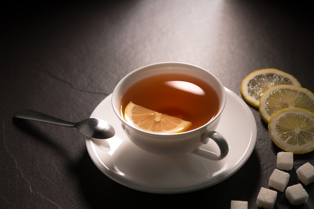 Taza de té con limón en la pared de granito negro