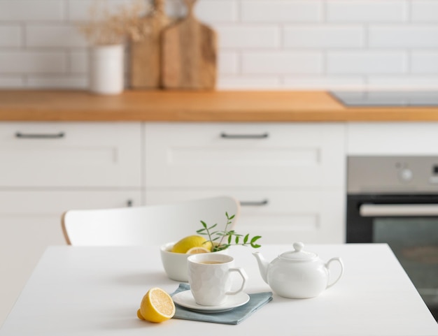 Foto una taza de té con limón y una tetera en una mesa blanca