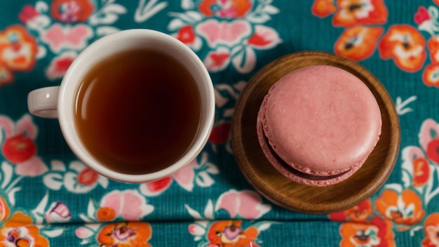 Una taza de té y macarrón en un mantel de color