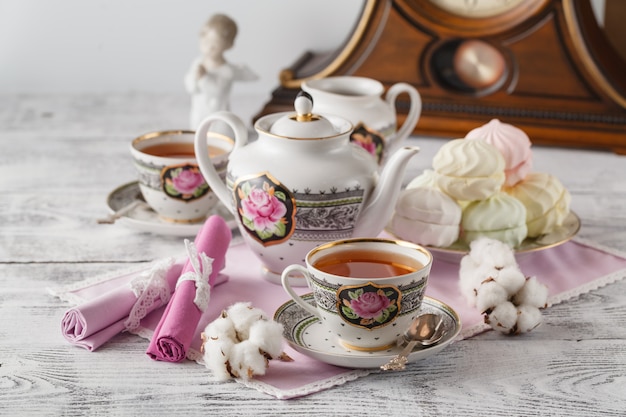 Taza de té y malvavisco con tetera sobre mesa blanca