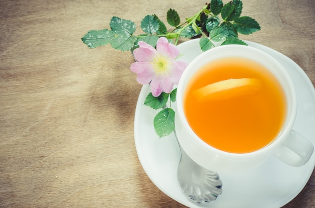 Taza de té de la mañana con limón y flores delicadas.