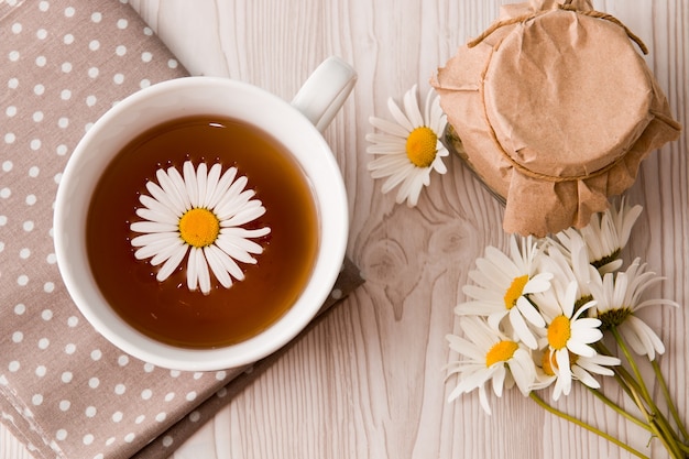 Taza de té y manzanilla y jar en un té de tela de lunares puede encaje gris marrón naranja beige flores