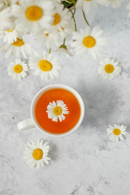 una taza de té con manzanilla y un ramo de margaritas