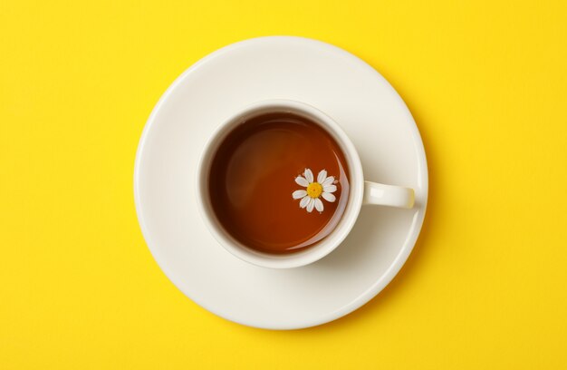 Taza de té de manzanilla sobre fondo amarillo