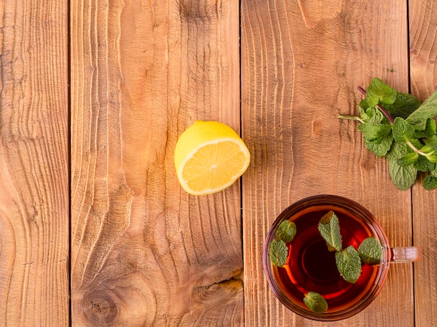 La taza de té con menta y limón en la mesa de madera marrón