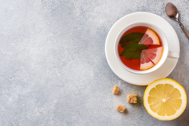 Taza de té, menta y limón sobre la mesa gris con fondo copyspace.