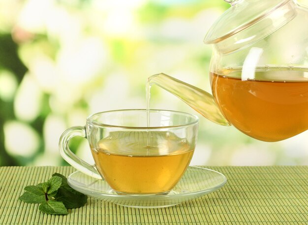 Taza de té con menta en la mesa sobre fundamentos brillantes