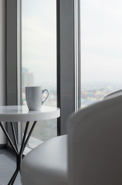 Taza de té en la mesa blanca junto a la ventana