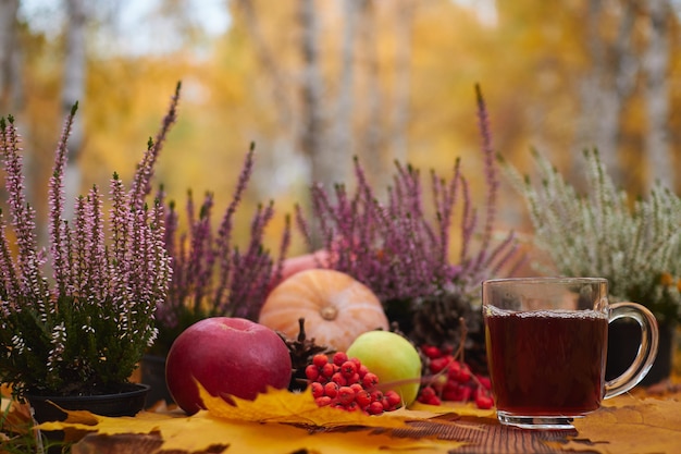 Taza de té en una mesa de madera con bayas y verduras de otoño