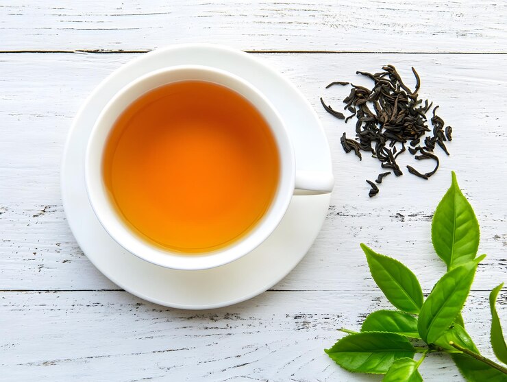 Una taza de té en una mesa de madera blanca decorada con hojas de té frescas y secas imagen generada por IA