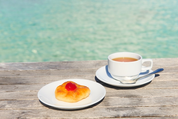 Una taza de té en la mesa con el mar al fondo