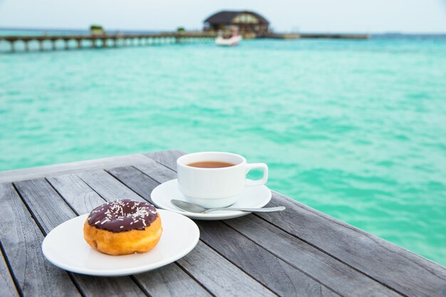 Una taza de té en la mesa con el mar al fondo