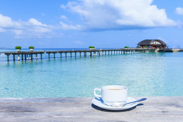 Una taza de té en la mesa con el mar al fondoxAxA