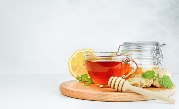 Taza de té, miel, limón y hojas de menta sobre fondo de hormigón gris