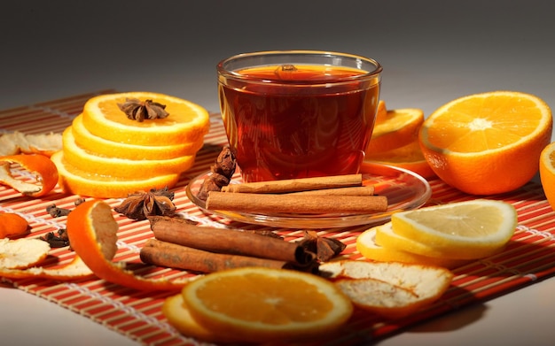 una taza de té con naranjas y canela y canela en una mesa