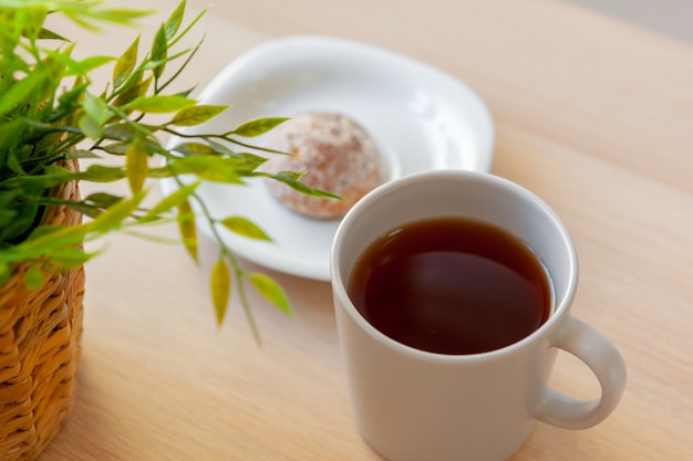 Taza de té negro caliente de cerca en la mesa de madera