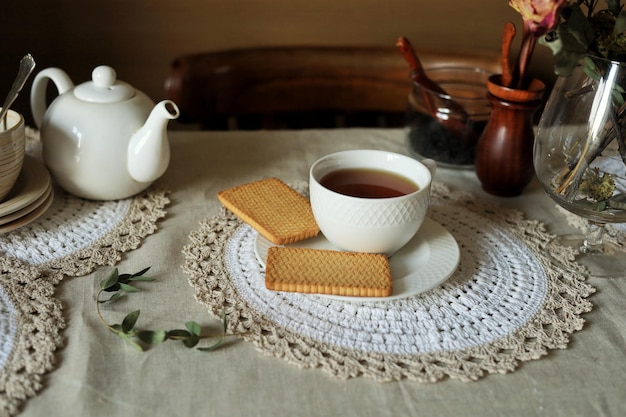 Una taza de té negro caliente en un platillo y galletas en la mesa Inicio bodegón Hora del té