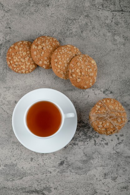 Taza de té negro con deliciosas galletas de avena sobre piedra.