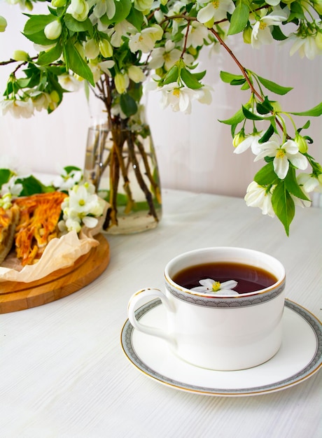 Una taza de té negro en flores de manzana blanca